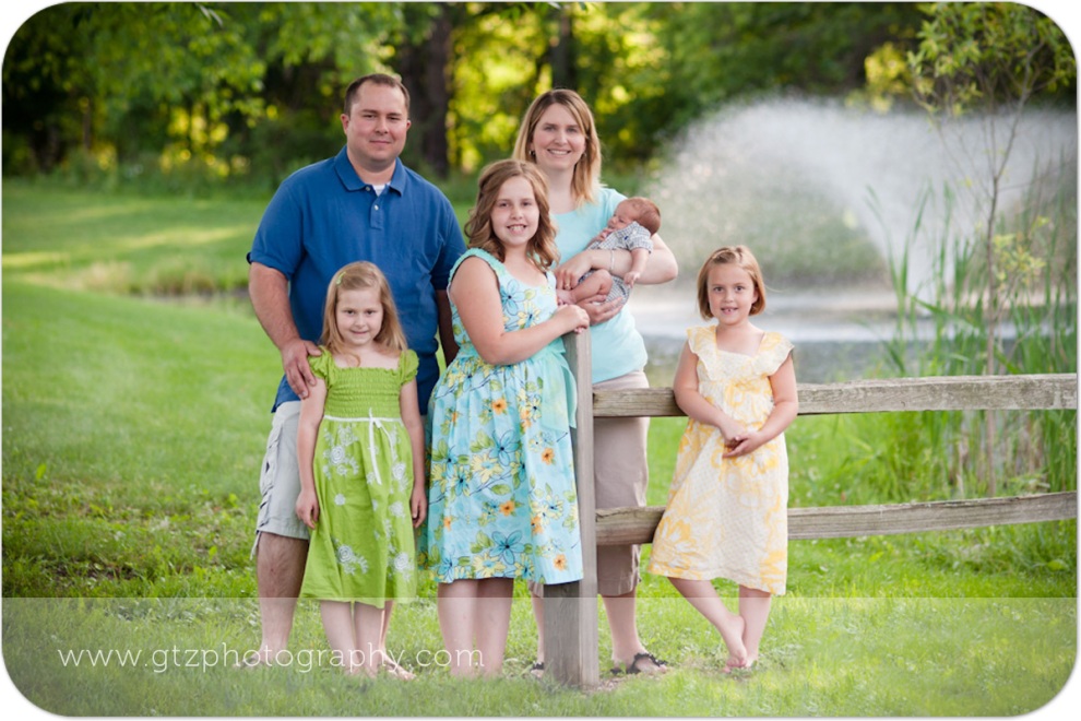 family portrait in a green setting with a fountain and pond in background